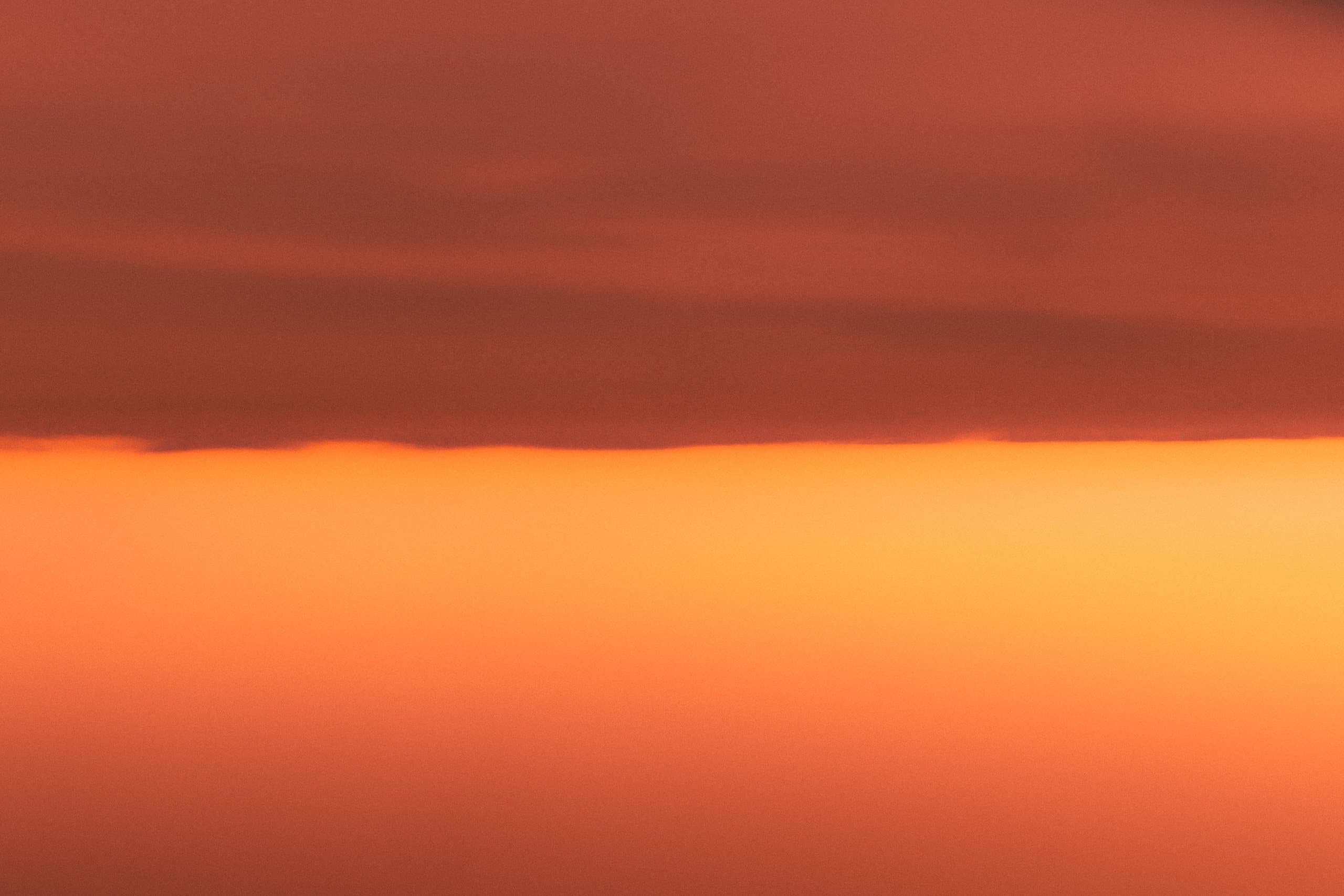 Eight Seconds, Sunrise, a photograph by Daniel Montero: a band of orange light beneath a dark red sky
